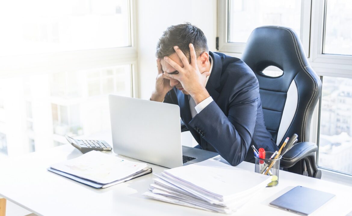 Jeune Homme D'affaires Stressé Assis Sur Son Lieu De Travail Au Bureau